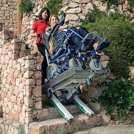 A person in a wheelchair is transported down a stone staircase with the Domino People electric wheelchair stair crawler