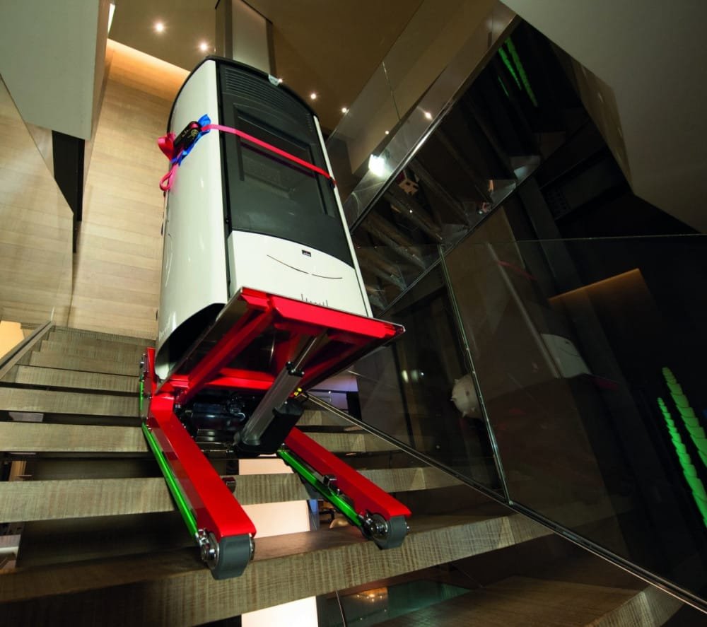 A  stair crawler transports an electric boiler up a wooden stairs